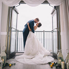 bride and groom embracing on lakeview's balcony overlooking water