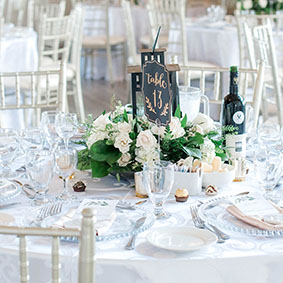 Guest table at Lakeview wedding with white linens and flower arrangements