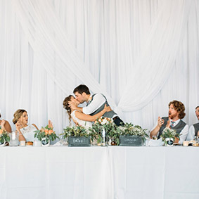 bride and groom kissing at head table during wedding reception at Lakeview in Hamilton