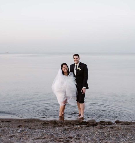 bride and groom laughing standing in the water at beach