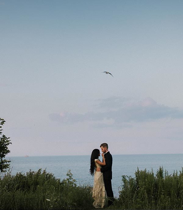 bride and groom embracing in front of lake ontario